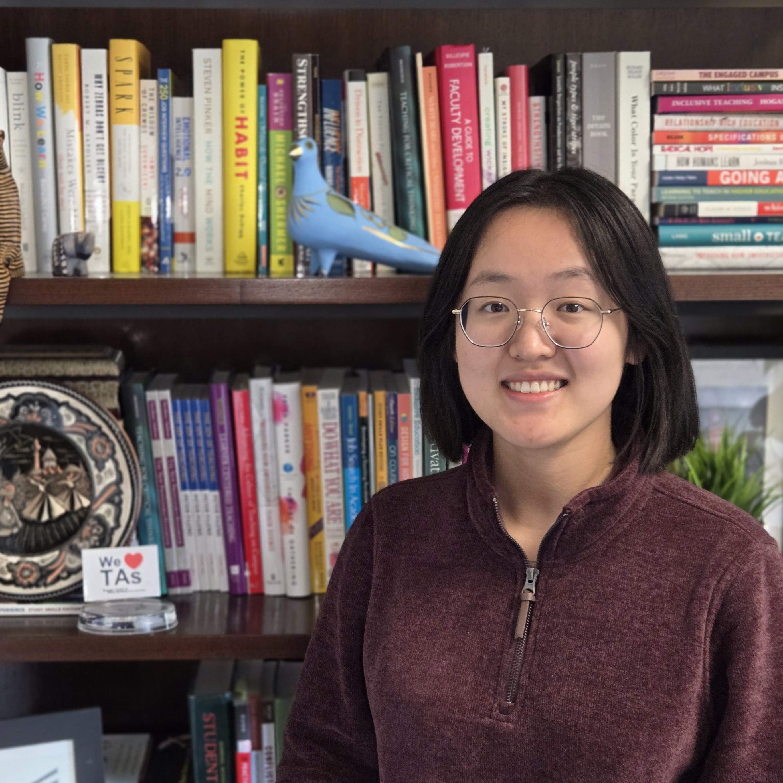 Chang smiling in front of a bookshelf