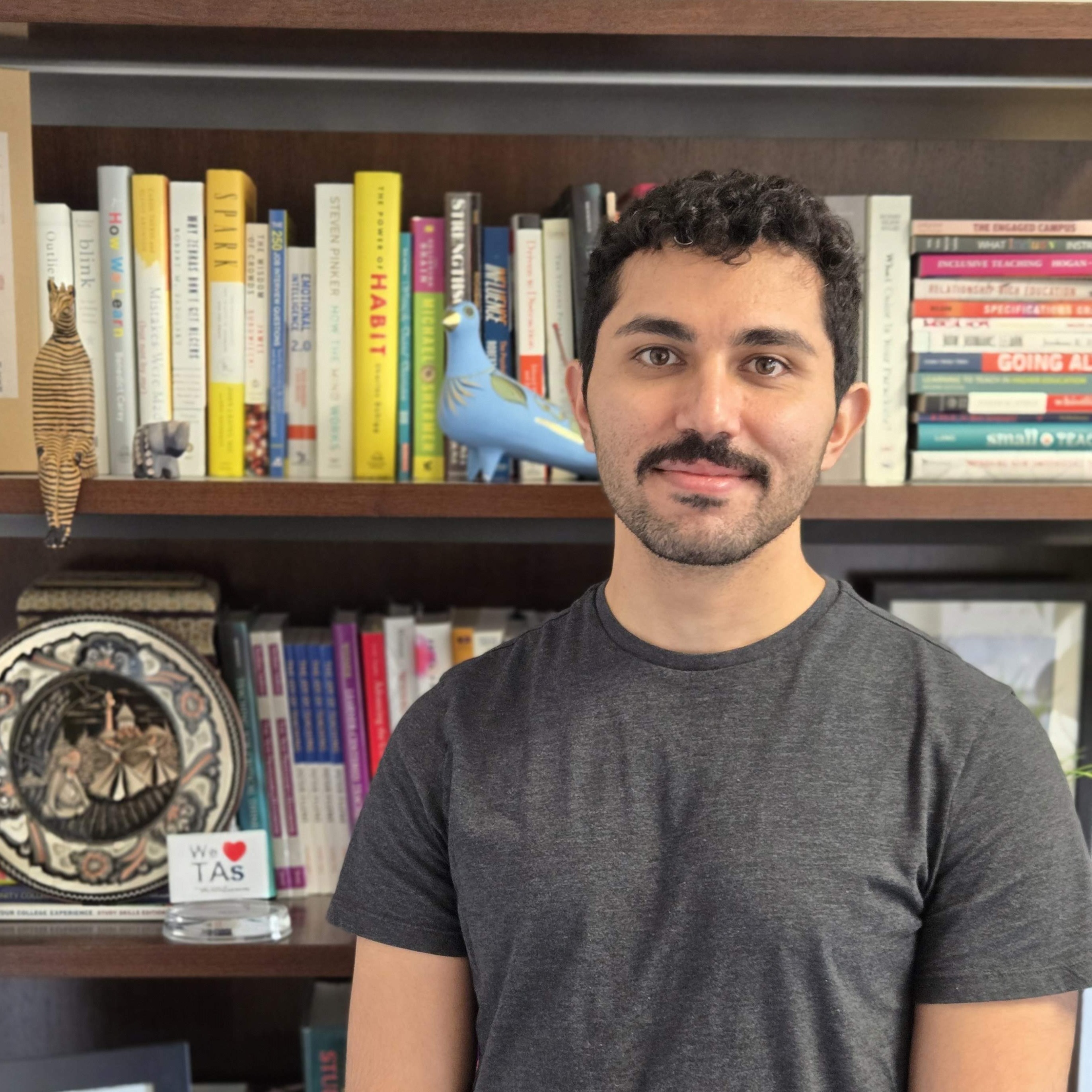 Ehsan smiling in front of a bookshelf