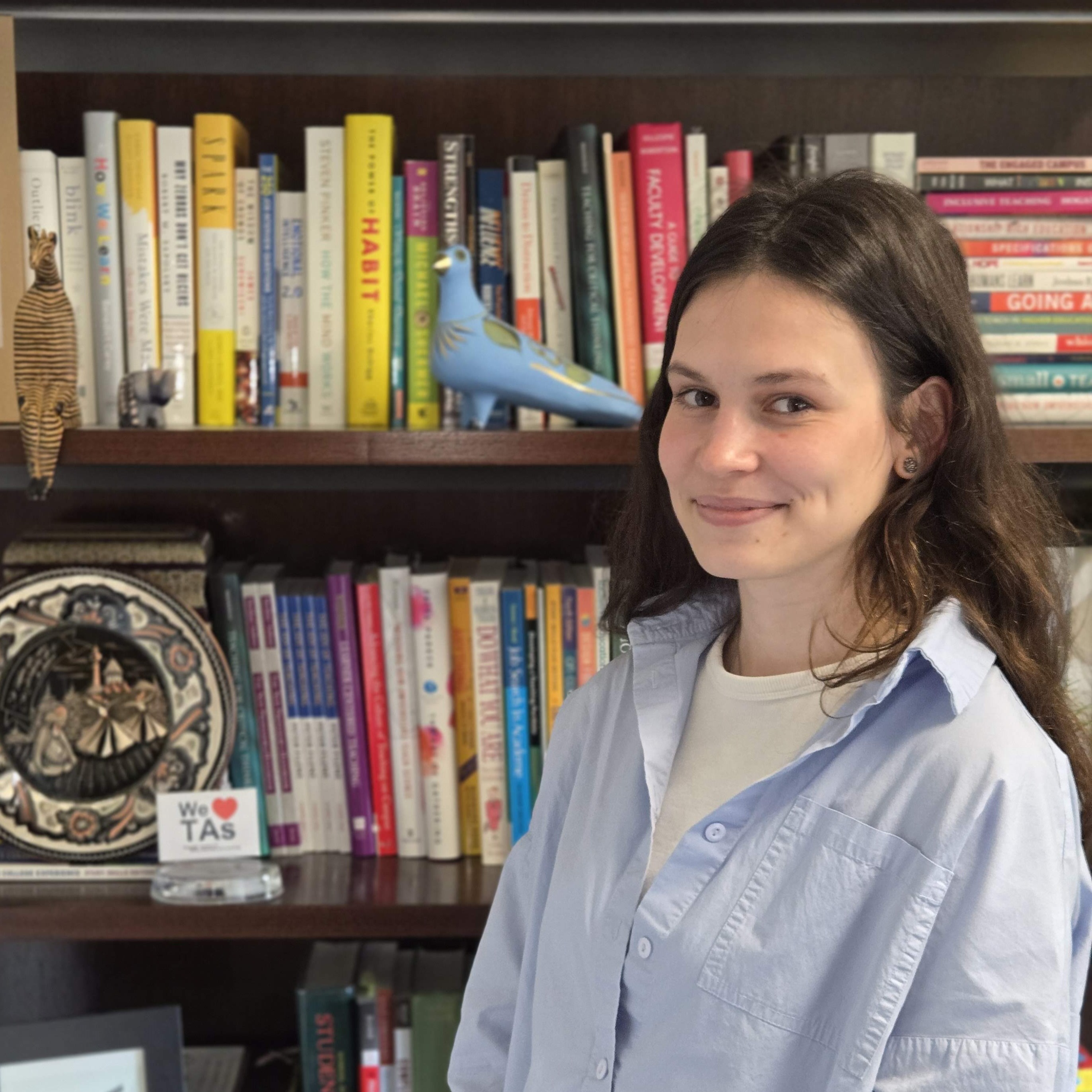 Kseniia smiling in front of a bookshelf