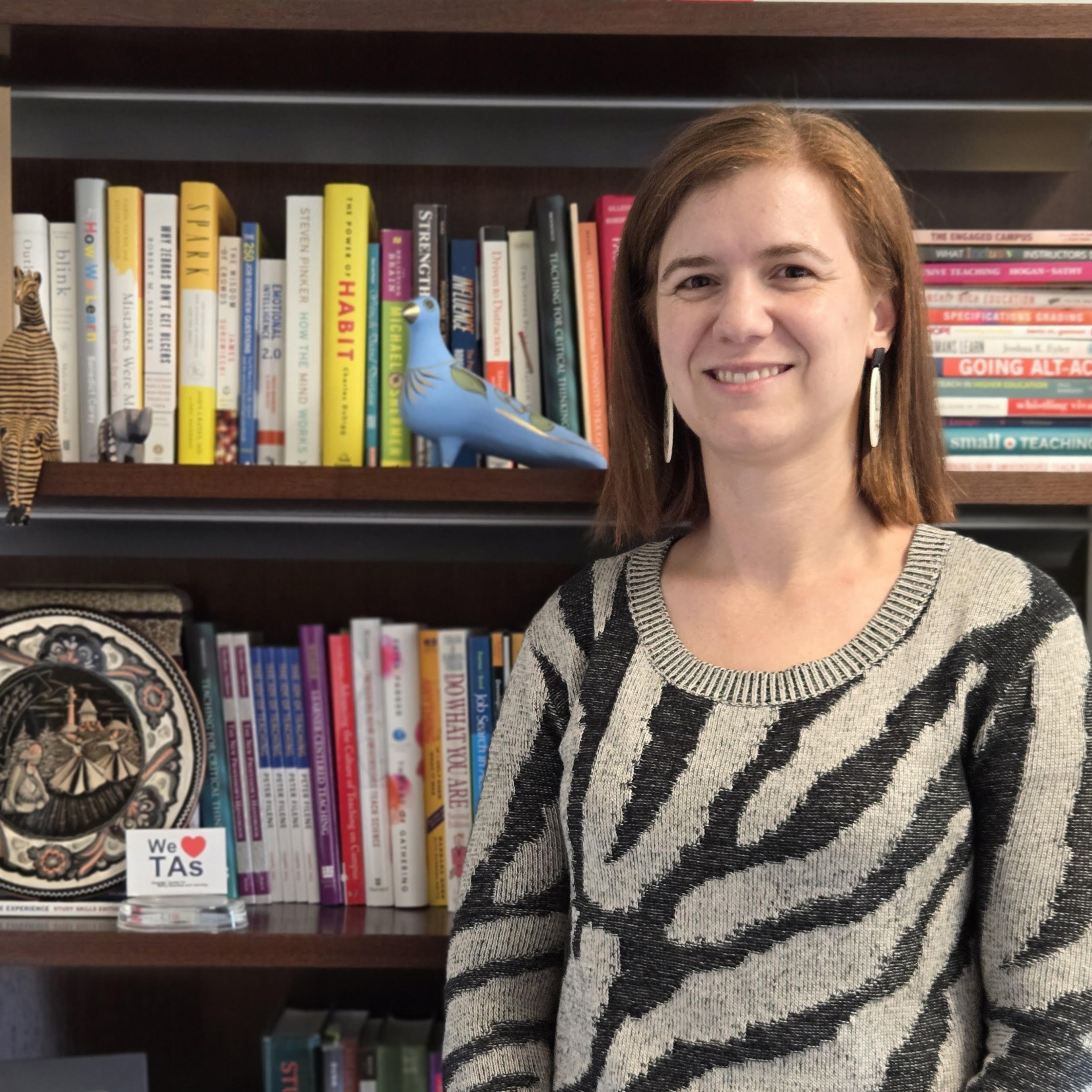 Ximena smiling in front of a bookshelf