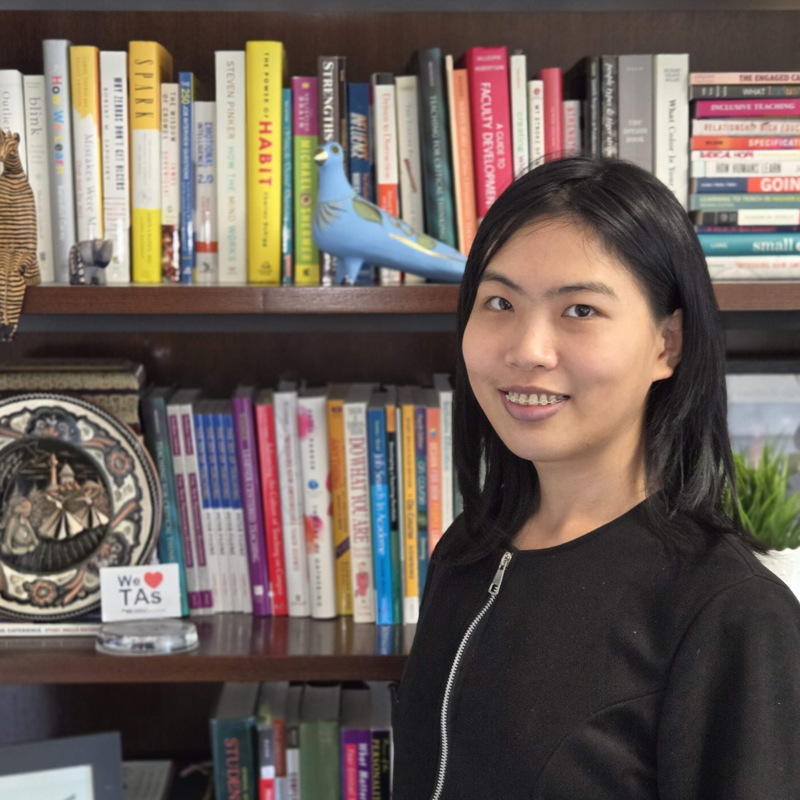 Yu smiling in front of a bookshelf