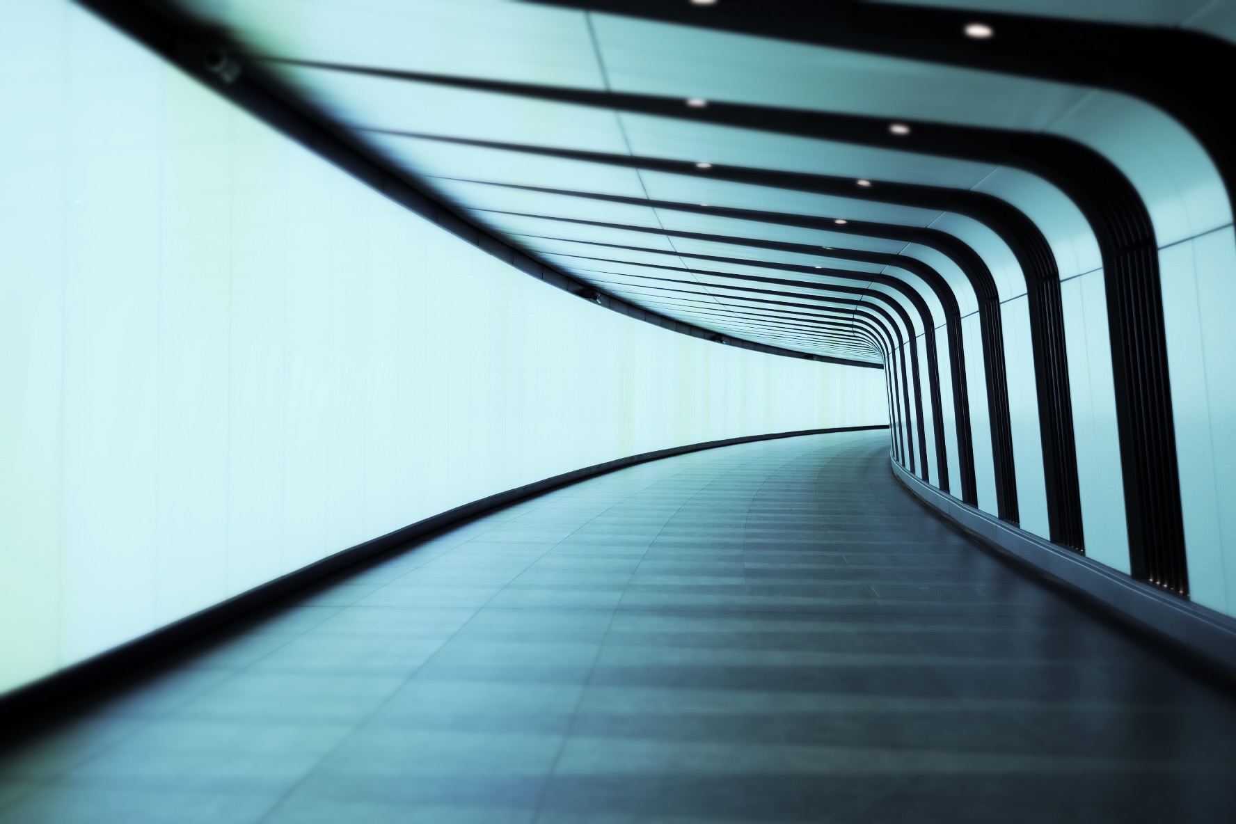 The photograph is of a curving corridor illuminated in light blue with curving black stripes along the ceiling and right side of the hallway. Used under a creative commons license. https://www.flickr.com/photos/mdales/49022996802/